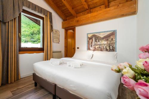 a bed in a room with a window and flowers at Hotel Aurora in Cimego