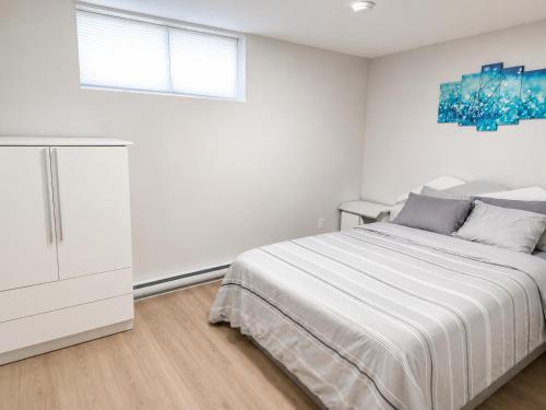 a white bedroom with a bed and a window at Quiet Haven - One-Bedroom Suite in Riverview
