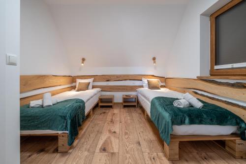 two beds in a room with wooden floors at Biała Owca in Biały Dunajec