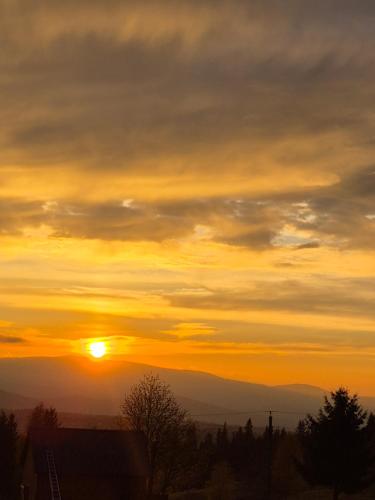 a sunset with the sun setting in the sky at Hill House Marisel in Mărişel