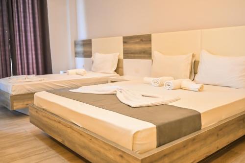 two beds in a hotel room with white sheets at Imperial Hotel in Tale