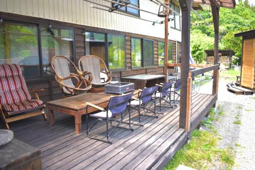 a wooden deck with chairs and a wooden table at 古民家宿まるもり in Wada