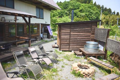a backyard with chairs and a fire pit and a cabin at 古民家宿まるもり in Wada