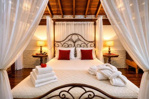 a bedroom with a bed with white sheets and red pillows at Estalagem Wiesbaden in Monte Verde
