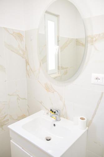 a white bathroom with a sink and a mirror at Imperial Hotel in Tale