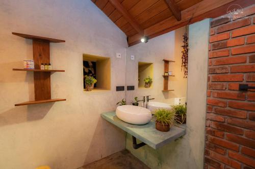 a bathroom with a sink and a brick wall at Heaven's Acres Lodge - Private one Bedroom Cabana in Matale