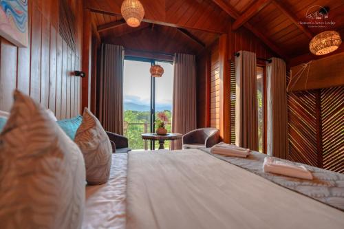 a bedroom with a large bed with a large window at Heaven's Acres Lodge - Private one Bedroom Cabana in Matale