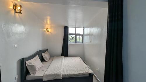 a small bed in a room with a window at Idembe Heritage in Gitarama