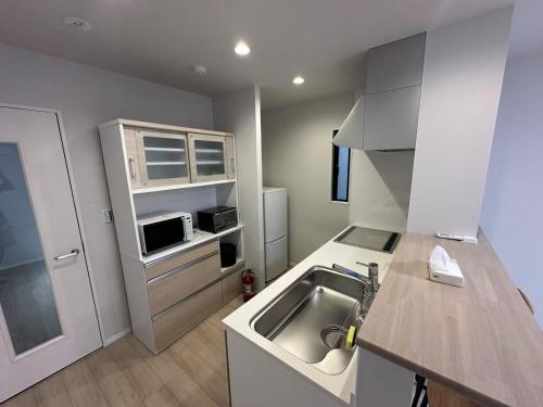 a small kitchen with a sink and a microwave at ドリームホテル住吉 in Sumiyoshi