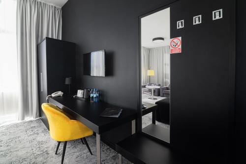 a black room with a desk and a yellow chair at Hotel Absolwent in Gostyń