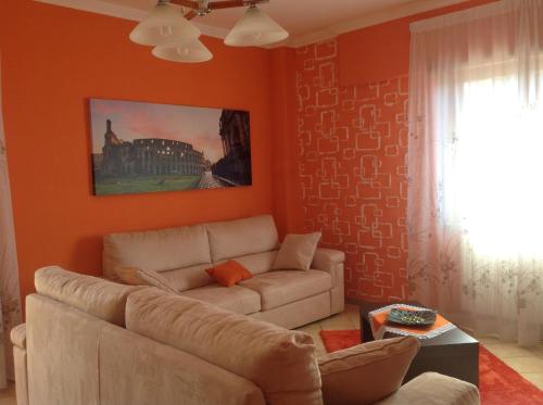 a living room with orange walls and a couch at Orange Holiday Home in Torvaianica