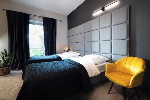 a bedroom with two beds and a yellow chair at Hotel Absolwent in Gostyń