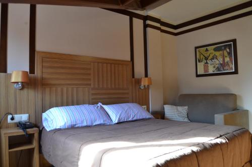 Un dormitorio con una cama grande y una silla. en Hotel Apartamentos Don Juan I, en Alcalá de Henares