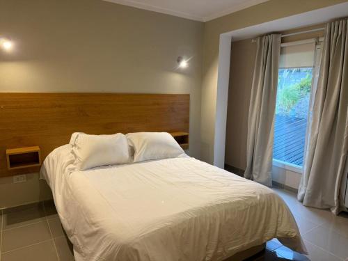 a bedroom with a white bed with a window at Apart Hotel Ostrón in Rada Tilly