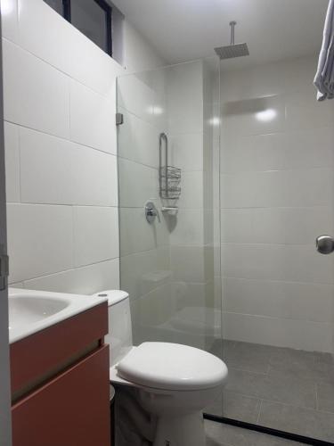a bathroom with a toilet and a glass shower at Student Site - Coliving Hotel in Montería