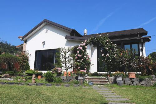 a white house with flowers in the front yard at Sarah's Small Garden in Cheonan