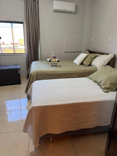 two beds in a hotel room with a table between them at Studio Lindo no coração de Picos in Picos
