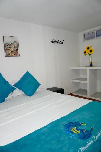 a bedroom with a white bed with blue pillows at MANDA PARaDISE HOUSE in Cartagena de Indias