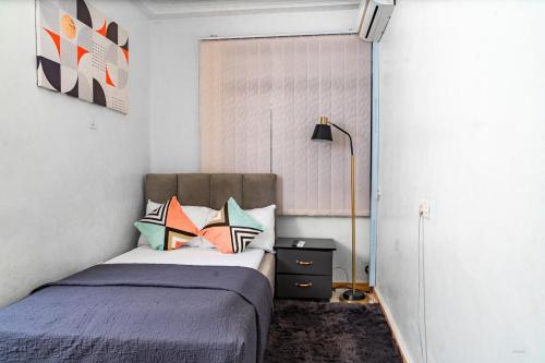 a bedroom with a bed with pillows and a lamp at Kumbaya Apartments in Achimota
