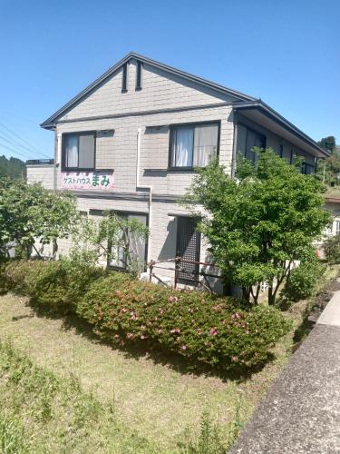 a gray house with bushes in front of it at guest house mami in Taketa