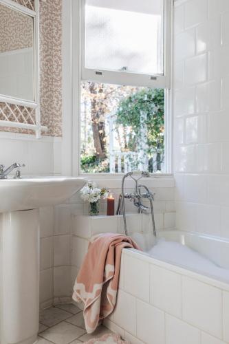 a bathroom with a tub and a sink and a window at Treehouse Southern Highlands in Moss Vale