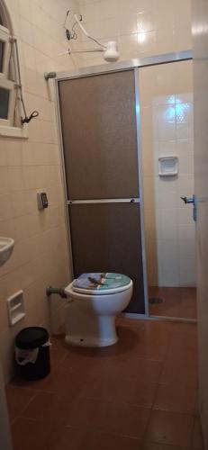a bathroom with a toilet with a glass shower door at Loft Praia do Sonho in Itanhaém