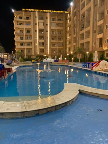 a large swimming pool at night with a large building at Biu Bela abartment hotel in El Alamein