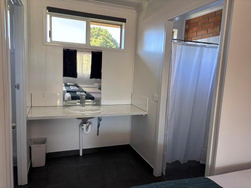 a bathroom with a sink and a mirror at Avocado Motor Inn in Childers