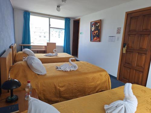 a room with three beds with swans on them at Hotel Calima in Quito