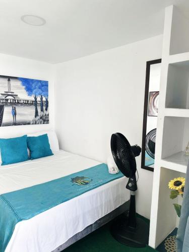 a bedroom with a bed and a desk with a fan at MANDA PARaDISE HOUSE in Cartagena de Indias