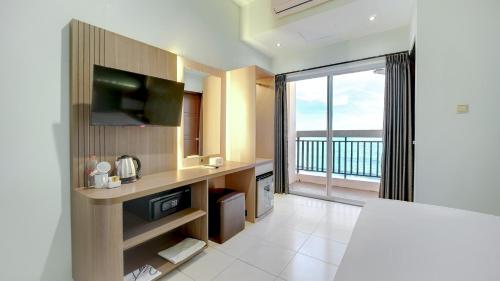 a kitchen with a television and a balcony with a view at Sun In Pangandaran Hotel in Pangandaran