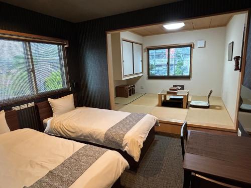 a room with two beds and a desk in it at 竹葉庵 in Nagaokakyo