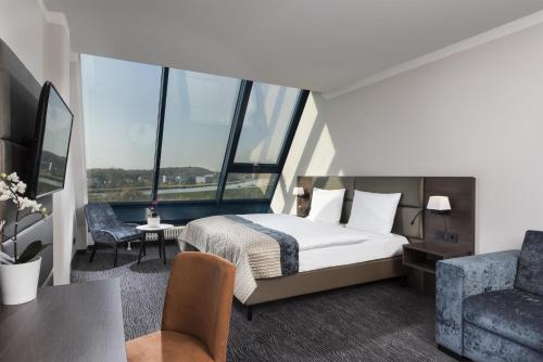a hotel room with a bed and a chair at Excelsior Hotel Nürnberg Fürth, a member of Radisson Individuals in Fürth