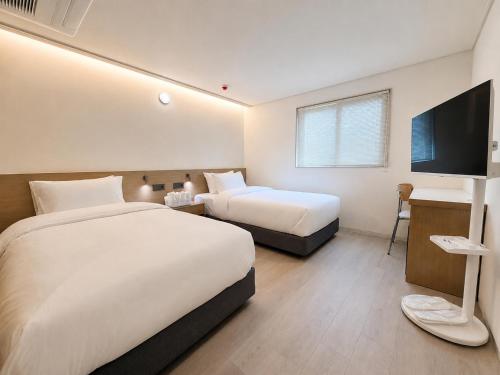 a hotel room with two beds and a flat screen tv at Link B Hotel in Busan