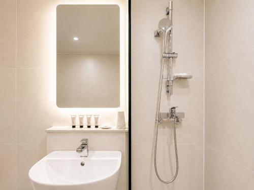 a bathroom with a shower and a sink and a mirror at Link B Hotel in Busan