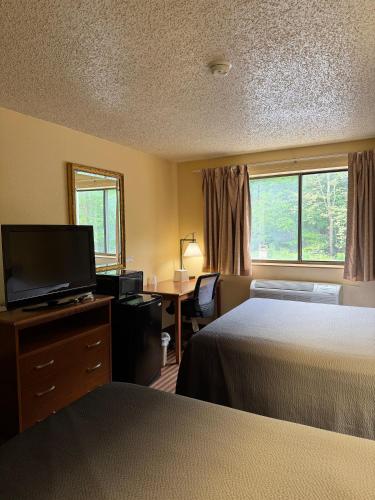 a hotel room with two beds and a flat screen tv at LaVale Inn Cumberland Area in La Vale
