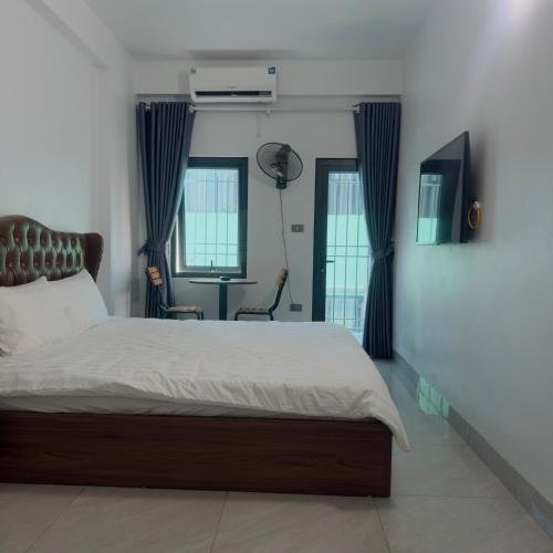 a bedroom with a large bed and two windows at Queen Hotel in Thạch Cầu