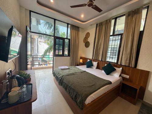 a bedroom with a bed and a tv and windows at Moon and Root in Narendranagar