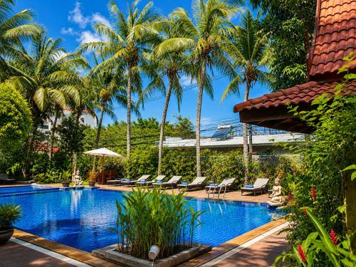a swimming pool with palm trees and lounge chairs at Nova Park Hotel Pattaya in Pattaya