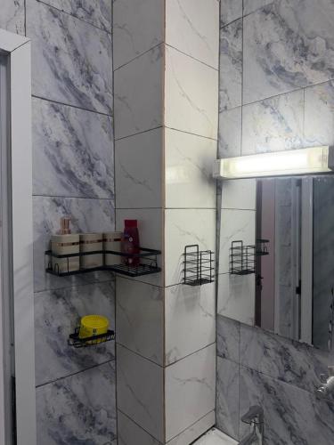 a bathroom with white marble walls and a mirror at Les résidences Merryke 1 in Abidjan