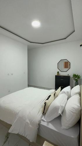 a bedroom with a white bed with white pillows at Les résidences Merryke 1 in Abidjan