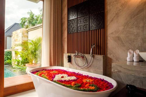 a bath tub filled with flowers in a bathroom at The Prime Seminyak by Kanaya Hospitality in Seminyak