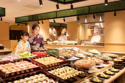 a woman and a little girl standing in front of a buffet at Ooedo Onsen Monogatari Premium Yamanaka Grand Hotel in Kaga
