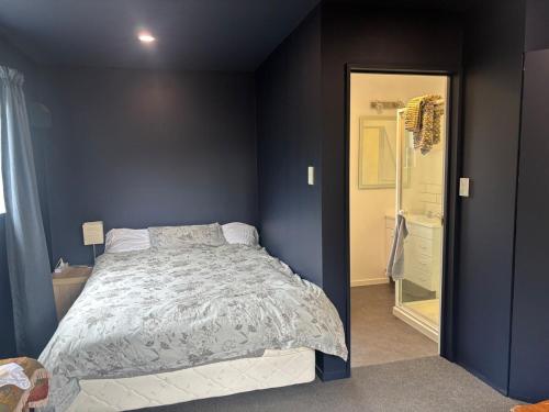 a bedroom with a bed and a blue wall at Private and comfortable guesthouse in Christchurch