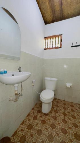 a bathroom with a white toilet and a sink at Waringin Homestay in Kuta
