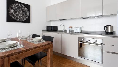 a kitchen with white cabinets and a wooden table at Italianway-Scarlatti in Milan