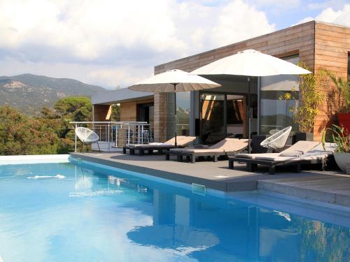 a swimming pool with two umbrellas and a house at Dililodge in Verghia