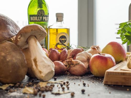 a table with apples and mushrooms and a bottle of alcohol at Hensens Residenz in Randerath