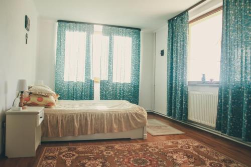 a bedroom with blue curtains and a bed with a rug at Casa Renti in Novaci-Străini