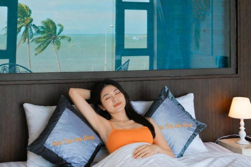 a woman laying on a bed with pillows at Sontra Sea Hotel in Danang